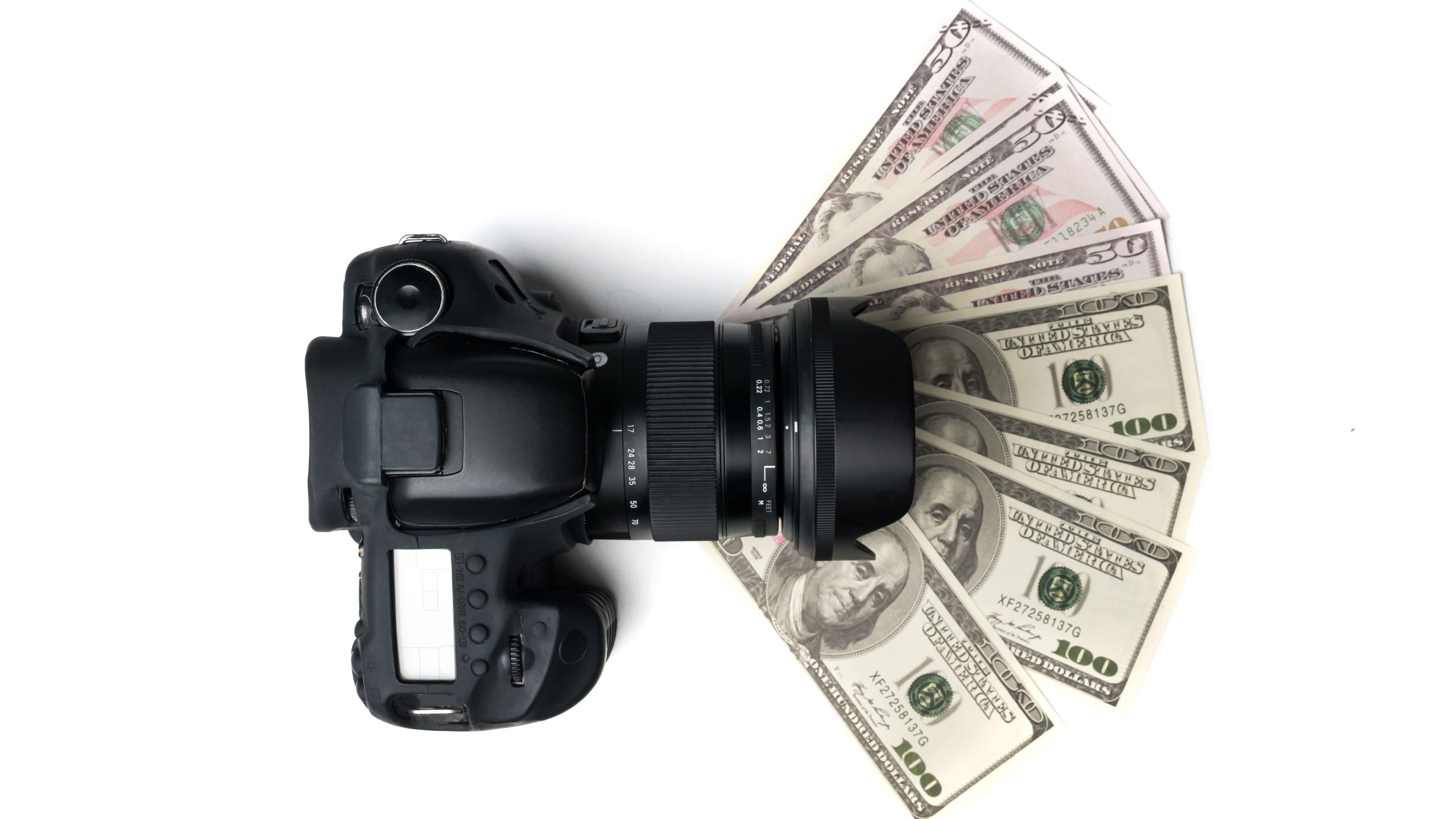 Top view of a black digital camera on banknotes with white background.